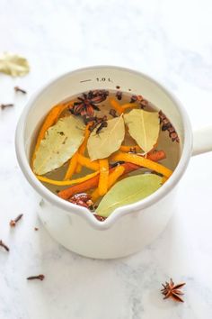 a white bowl filled with soup next to an orange peel and star anise on the side