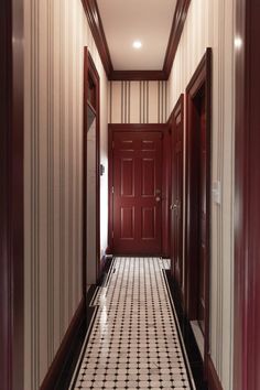 an empty hallway with red doors and black and white floor tiles on either side of the door