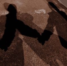 the shadow of two people holding hands walking down a street with a stop sign in the background