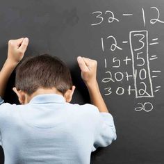 a young boy writing numbers on a blackboard