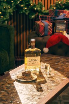 a bottle of whisky sitting on top of a table next to some cookies and glasses