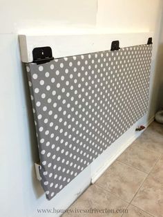 a white and gray polka dot privacy wall in the corner of a room with tile flooring