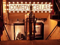 a sign that is on the side of a building with lights around it and an open door