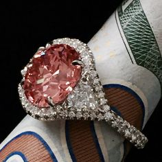 a pink diamond ring sitting on top of a roll of toilet paper