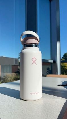 a white water bottle sitting on top of a table next to a window with blue sky in the background