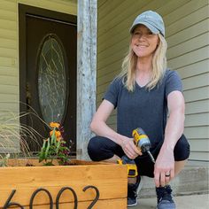 a woman is sitting on the front porch with her tool and planter in hand