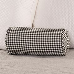 a black and white checkered pillow sitting on top of a bed next to pillows