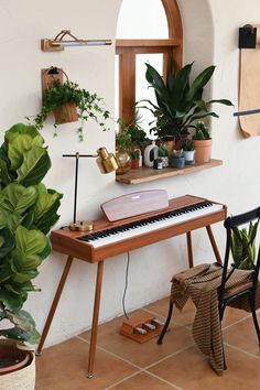 a piano sitting on top of a tiled floor next to a potted plant and window