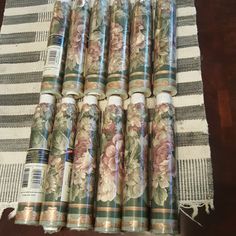 six rolls of wrapping paper sitting on top of a striped tablecloth with floral designs