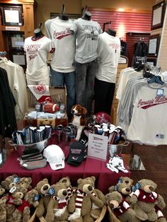 two people standing behind a table with teddy bears and other items on display in front of them