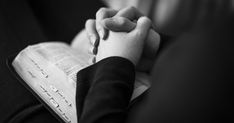 a person holding the hands of another person who is sitting down and reading a book