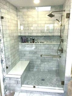 a walk in shower sitting next to a white tiled wall and floor with a glass door