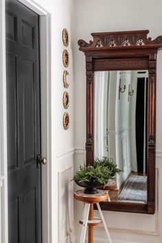 a mirror sitting on top of a wooden table next to a plant in a pot