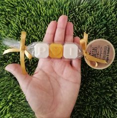 a hand holding an empty pill bottle in front of green grass with a yellow ribbon around it