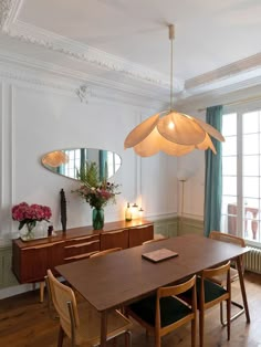 a dining room table with chairs and a lamp hanging from it's center point