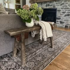 a living room with a gray couch and wooden table on top of carpeted floor