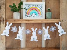 some paper bunnies are hanging on a shelf next to a potted plant and a rainbow