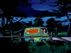 the van is driving down the road in front of some trees and bushes at night