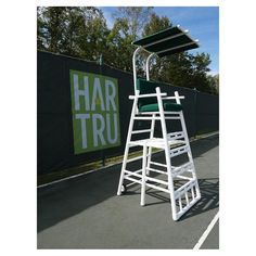 a white ladder sitting on top of a tennis court next to a green sign that says har tru