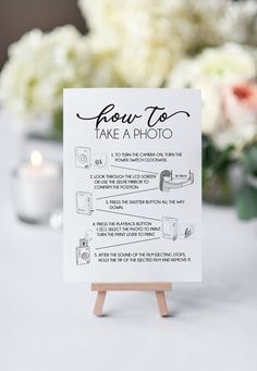 a table with a sign that says how to take a photo and flowers in the background