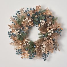 a christmas wreath with pine cones, berries and other holiday decorations on a white background