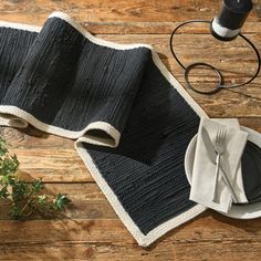 a table setting with black and white placemats, silverware and napkins