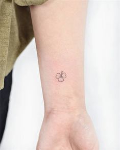 a small four leaf clover tattoo on the wrist