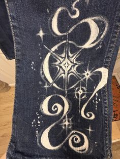 the back of someone's jean jacket with an artistic design on it and stars in the sky