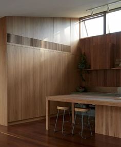 a kitchen with wooden cabinets and stools next to a table in front of a window