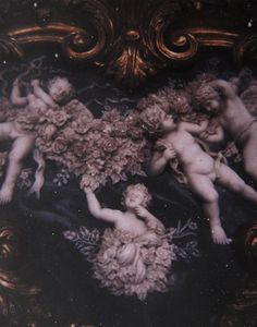 three cherubs surrounded by flowers in an ornate frame