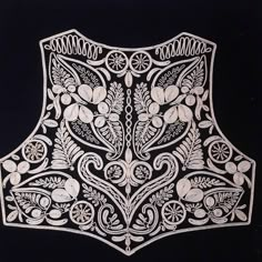 an intricately designed piece of cloth with flowers and leaves on black background, in the shape of a vest