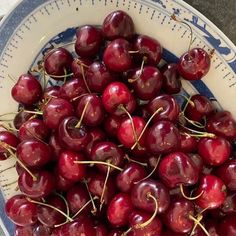 a blue and white bowl filled with cherries