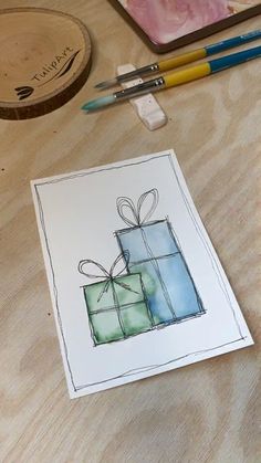 a watercolor drawing of two wrapped presents on a table with markers and pencils