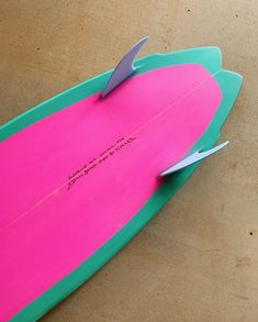 a pink and green surfboard laying on the ground