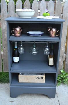 an old bookcase turned into a bar with wine glasses and plates on the shelf