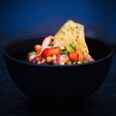 a black bowl filled with salsa and tortilla chips