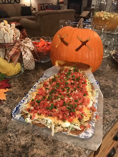 a pizza on a table with a jack - o'- lantern pumpkin in the background