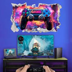 a person holding a video game controller in front of a tv with a wall decal behind it