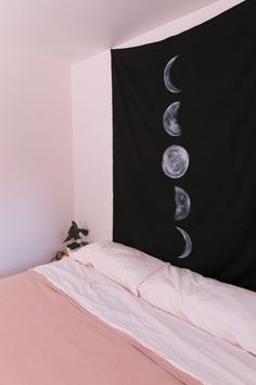 a black and white photo of the moon phases on a wall behind a bed with pink sheets