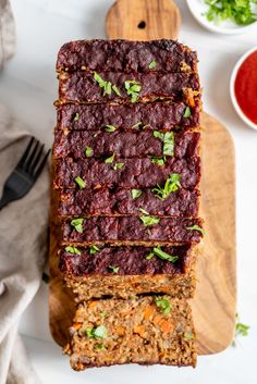 sliced meatloaf on a cutting board with sauces and garnishes