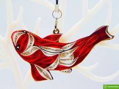 a red fish is hanging from a white tree ornament on a black cord