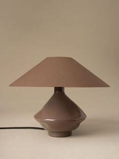 a table lamp with a brown shade on it and a cord plugged into the base