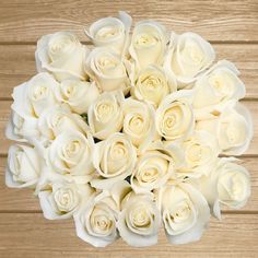 a bouquet of white roses sitting on top of a wooden table