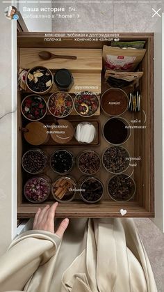 a person holding up a wooden box filled with spices and condiments in it