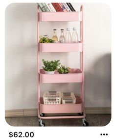 a pink shelf with books and plants on it