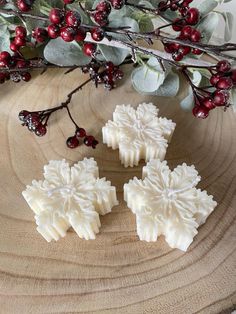 three snowflake shaped soaps sitting on top of a wooden table next to berries