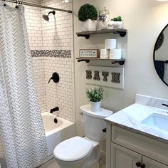 a white bathroom with black and white accessories on the shelves above the toilet, shower curtain, and bathtub