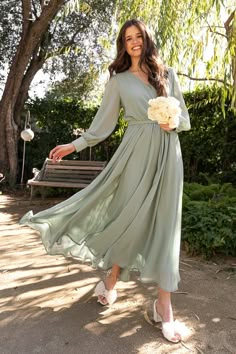 a woman in a green dress is posing for the camera with her hand on her hip