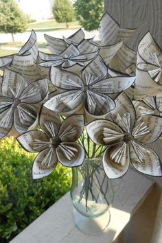 a vase filled with paper flowers sitting on top of a window sill