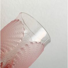 a glass filled with pink liquid sitting on top of a white countertop next to a wall